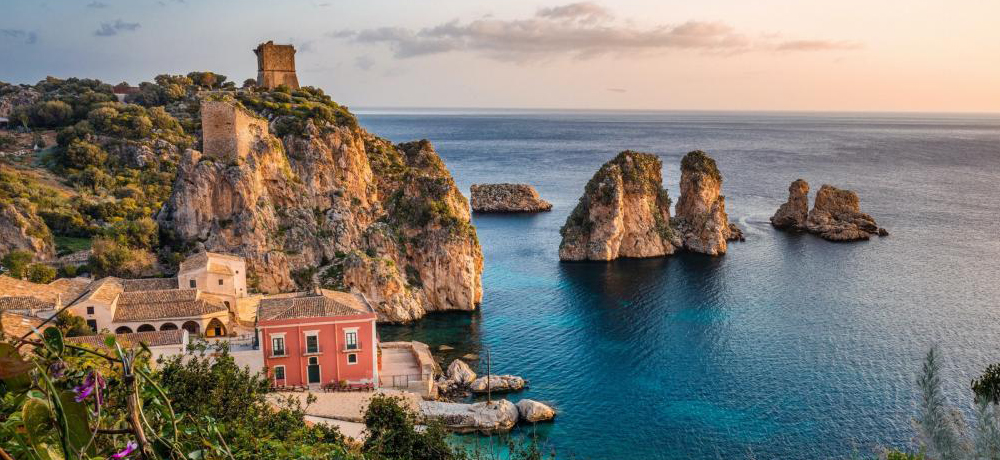 Cliffs of Sicily with buildings, ruins and the sea.
