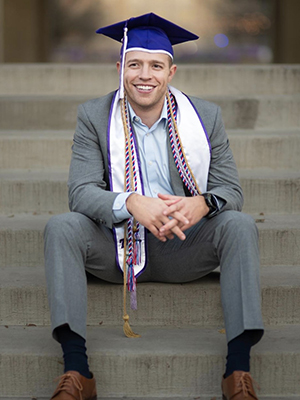 Max Muskat in cap and cords sitting on steps