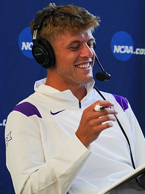 Luke Swan in front of an NCAA backdrop wearing a headset