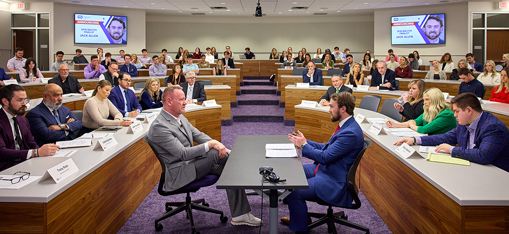 Section Image: Student pitching to Ken Corbit while judges and other students observe 