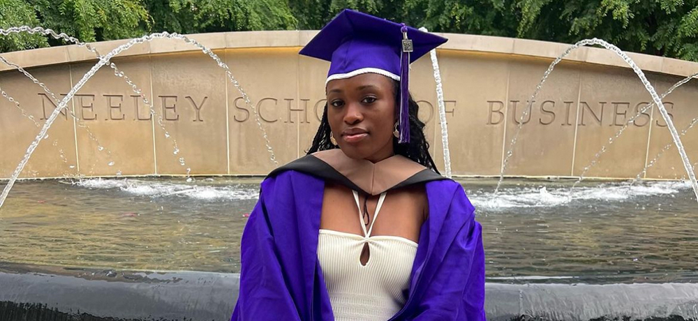 Tomi Taiwo in graduation cap and gown by the Neeley fountain