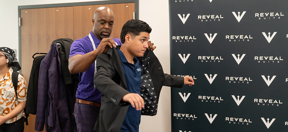 Student being helped into a suit jacket