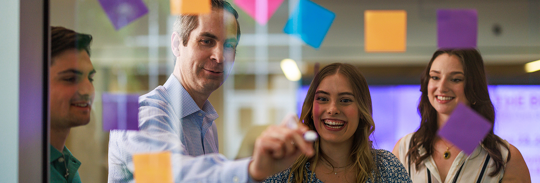 Section Image: Tyson Browning with students with post-its on a glass wall 