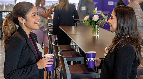 Two girls with purple TCU cups at an event