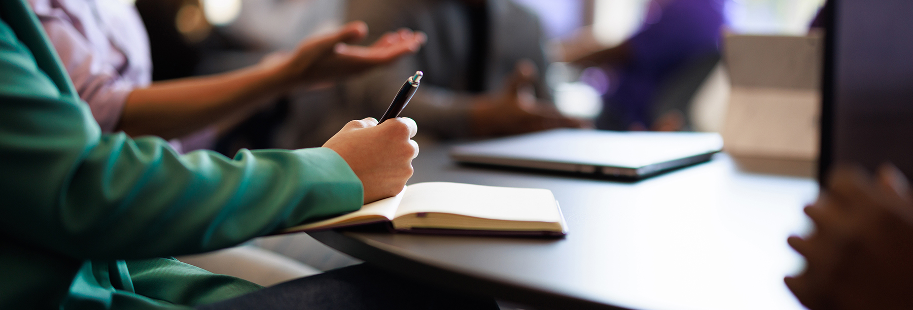 Section Image: Notepad on table and women with pen in hand 