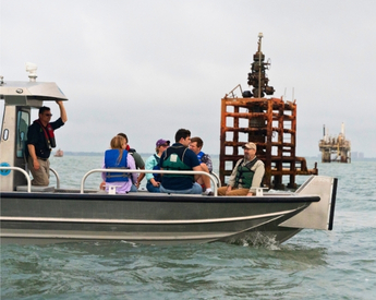 Group of TCU students and advisors with Texas General Land Office on a boat next to an orphan well