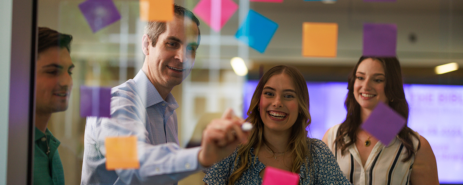 Professor and students ideating with sticky notes