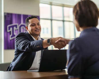TCU Neeley faculty shaking hands over a desk