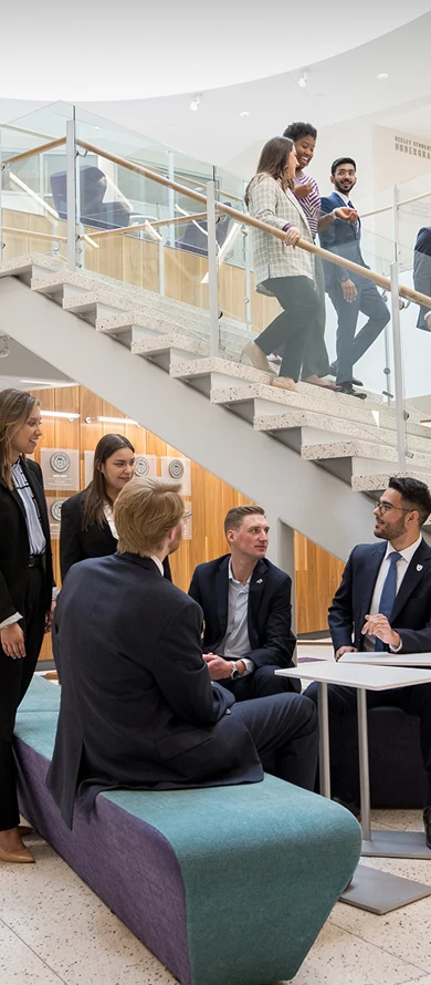Students gathered around tables and walking down stairs in the Neeley School of Business