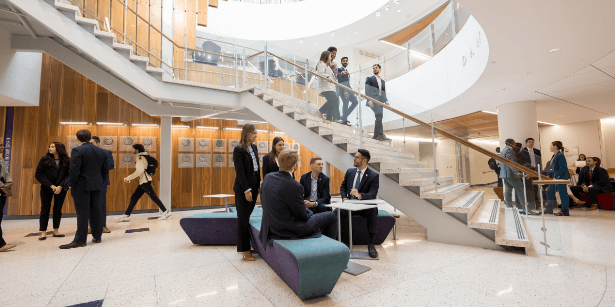 Students walk down the staircase and gather in the atrium of Neeley. 