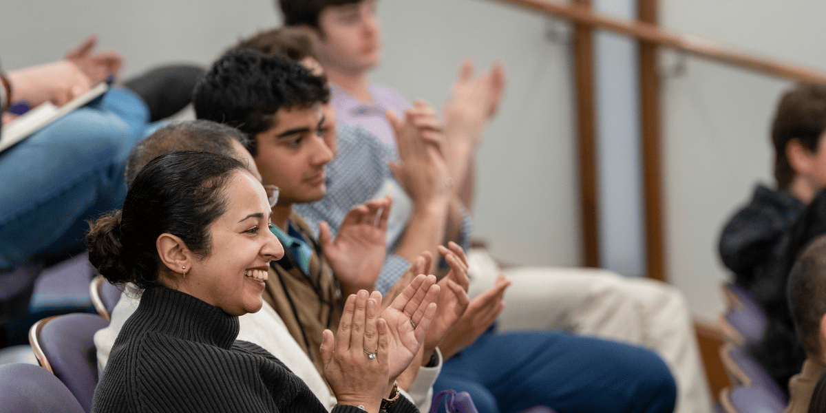 An engaged audience at the 2026 AI Forward Symposium applaud the speakers. 