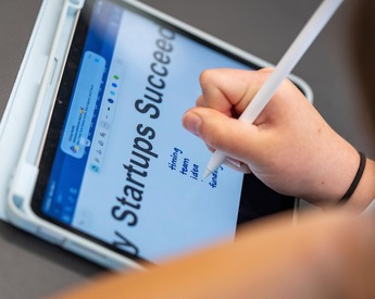 Student taking notes on startup success presentation