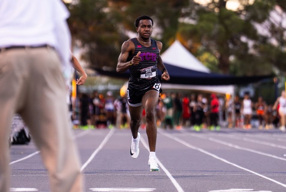 Male track athlete competes in a race and runs toward the finish line. 