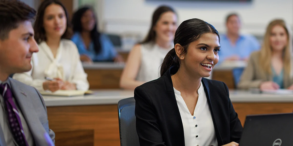 An Accounting student asks a question while working on a laptop in class