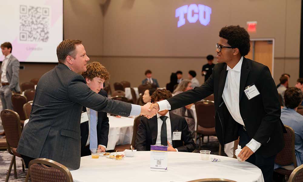 Neeley Mentorship Program mentor and mentee shaking hands across banquet table