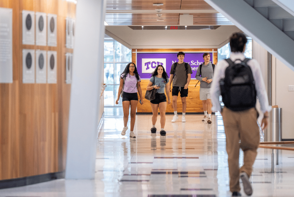 Undergraduate students walking on the first floor of Neeley between Tandy Hall and the Rogers Rotunda. 