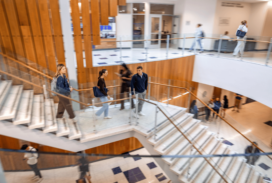 Undergraduate students walk on the Rogers Rotunda stairway at the center of Neeley's building.