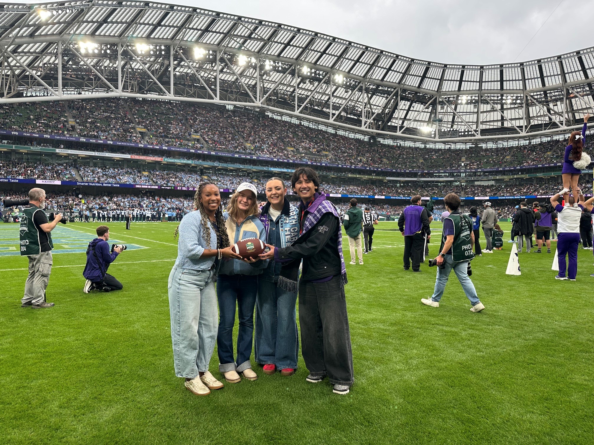 The winning team in the Ireland business case competition pose together on the field during the football game.